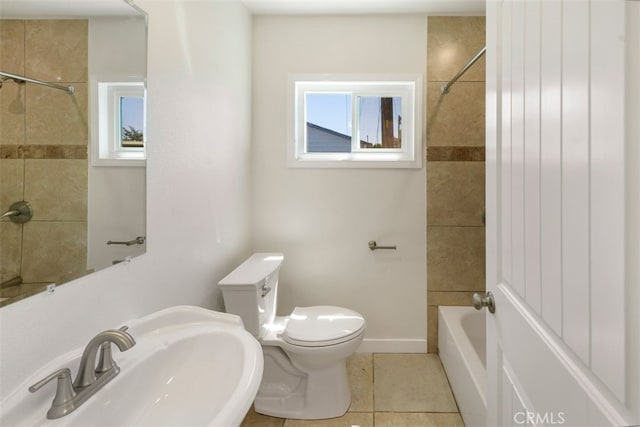 full bath with baseboards, toilet, tile patterned floors, shower / washtub combination, and a sink