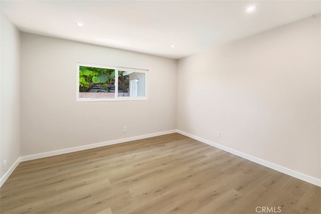 empty room with light wood-type flooring, baseboards, and recessed lighting