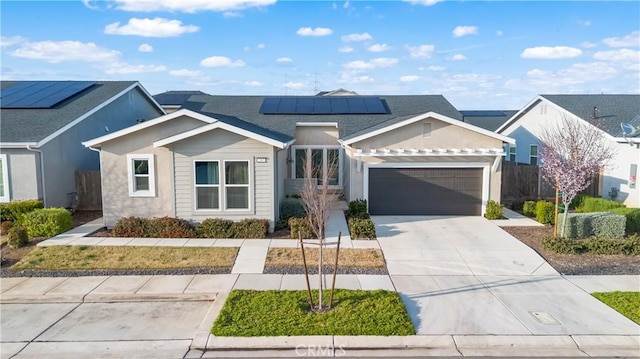 view of front of property featuring solar panels, driveway, an attached garage, and fence