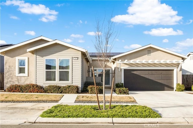 ranch-style house with a garage, driveway, solar panels, and stucco siding