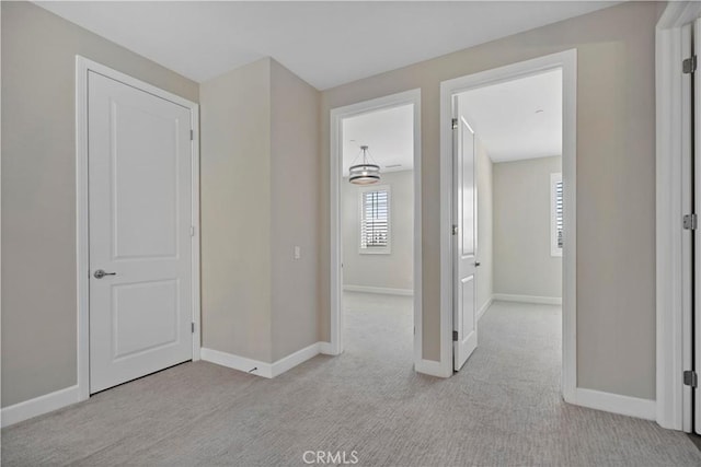 hallway featuring light carpet and baseboards