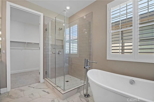 full bathroom with a freestanding tub, baseboards, marble finish floor, a spacious closet, and a shower stall