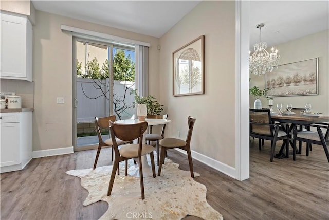 dining room with a notable chandelier, baseboards, and wood finished floors