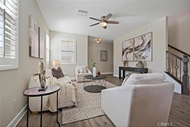 living area with visible vents, stairway, baseboards, and wood finished floors