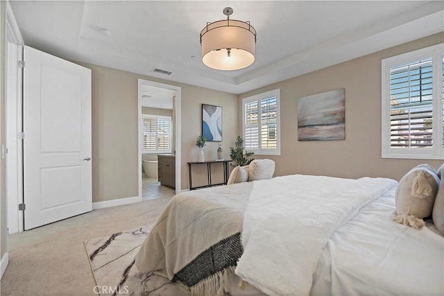 bedroom featuring connected bathroom, carpet floors, visible vents, baseboards, and a raised ceiling