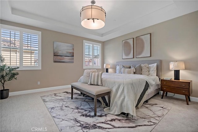 bedroom featuring baseboards, a tray ceiling, and light colored carpet