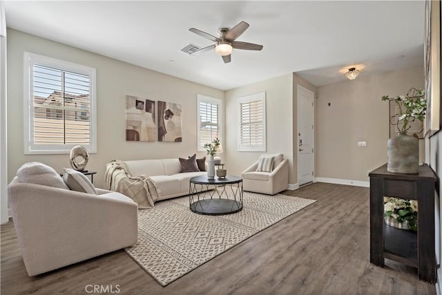 living room featuring baseboards, visible vents, ceiling fan, and wood finished floors