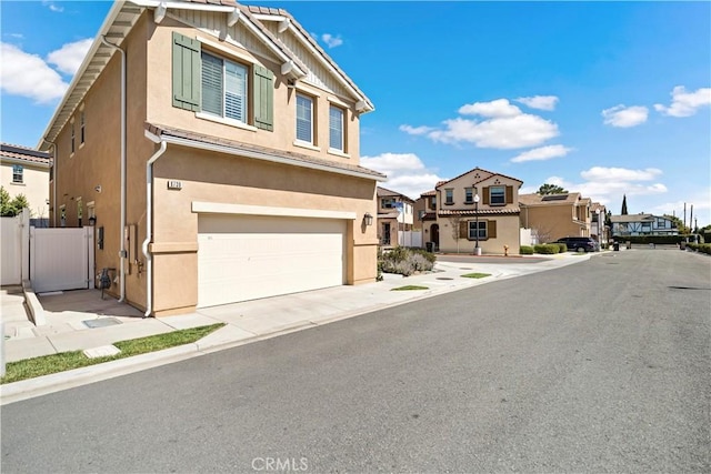 view of front of house featuring a garage, fence, a residential view, and stucco siding