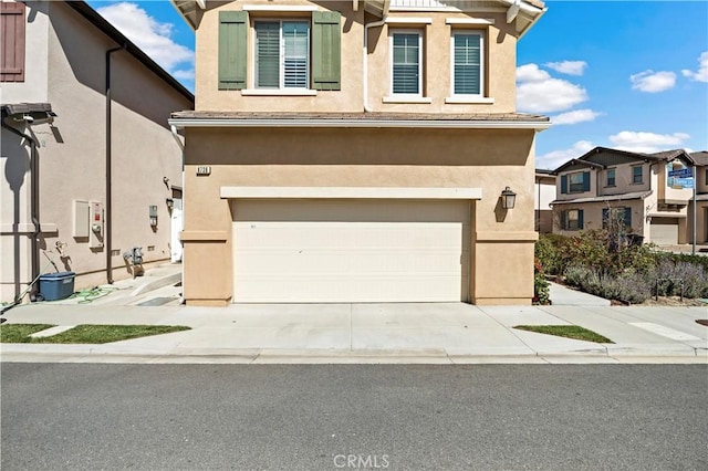 view of front of property with a garage, concrete driveway, and stucco siding