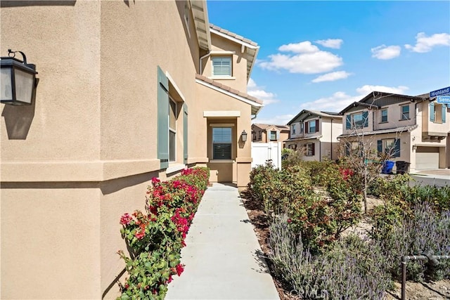 entrance to property with fence, a residential view, and stucco siding