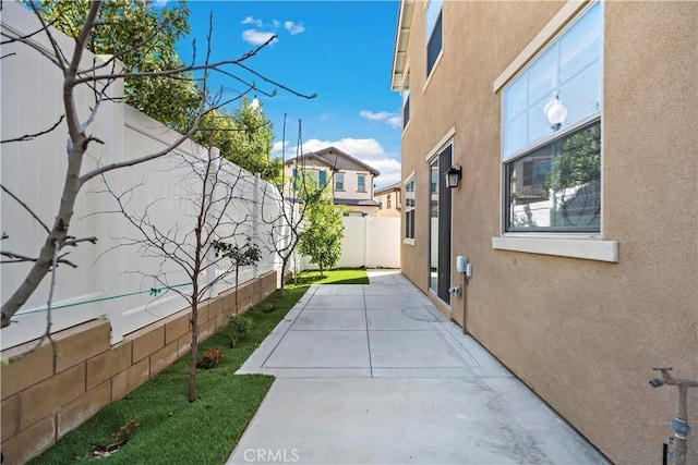 view of side of home featuring a fenced backyard, a patio, and stucco siding