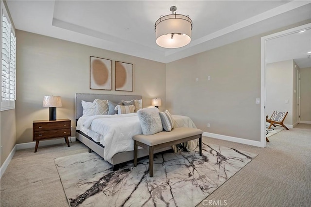 bedroom featuring carpet floors, baseboards, and a raised ceiling