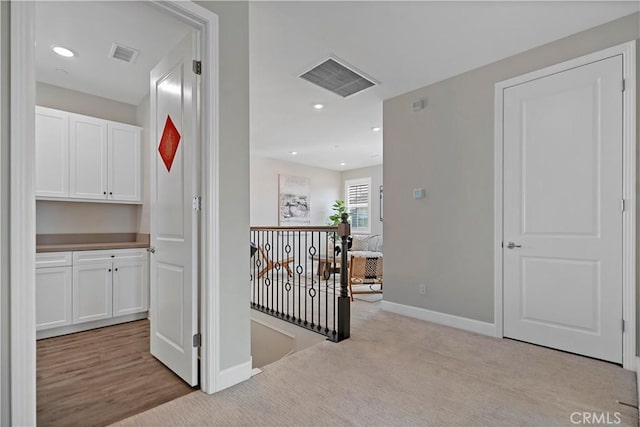 hall with visible vents, carpet, an upstairs landing, and baseboards