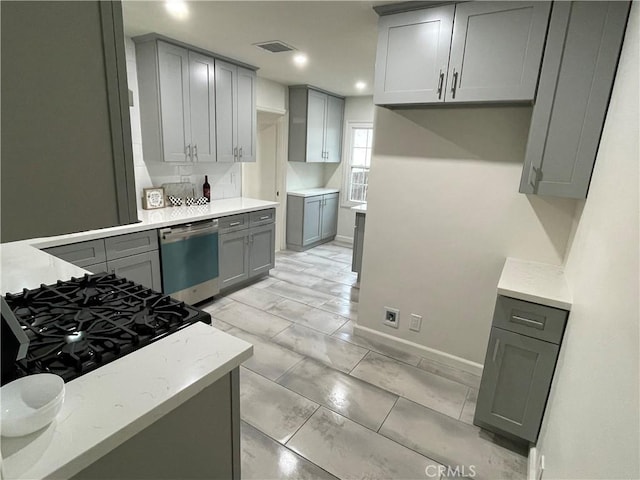 kitchen with visible vents, light stone counters, dishwasher, and gray cabinetry