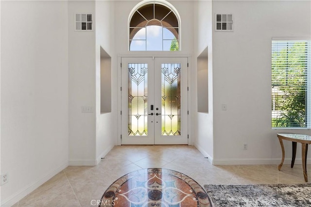 foyer entrance with visible vents, a wealth of natural light, and tile patterned floors