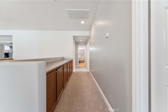 corridor featuring baseboards, visible vents, and light colored carpet