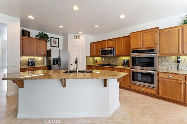 kitchen featuring visible vents, appliances with stainless steel finishes, light stone counters, and a sink