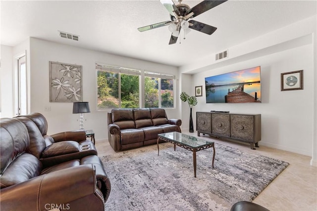 living room with a ceiling fan, visible vents, and baseboards