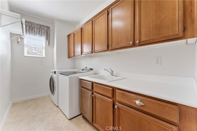 laundry area with light tile patterned floors, a sink, baseboards, cabinet space, and washer and clothes dryer