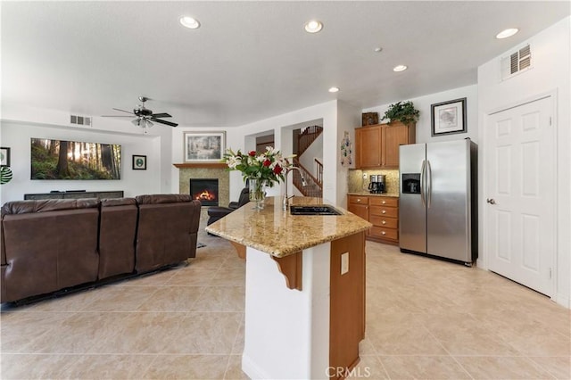 kitchen featuring a sink, stainless steel fridge, visible vents, and brown cabinets