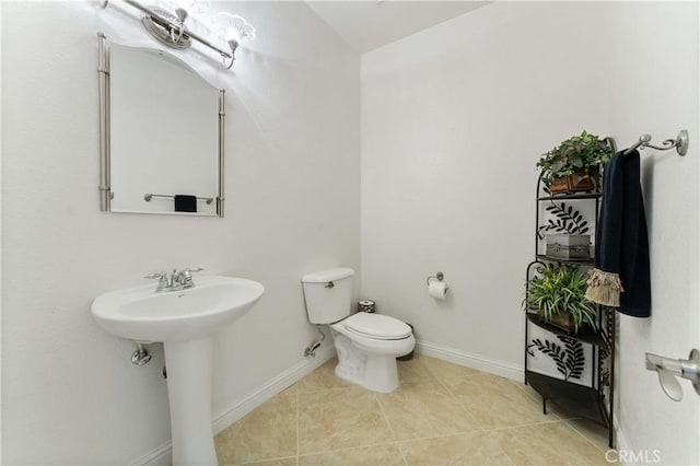 half bath featuring tile patterned flooring, baseboards, a sink, and toilet