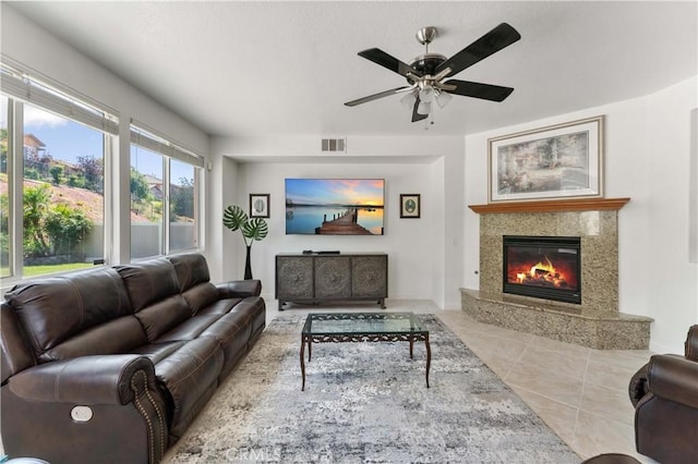 tiled living area featuring a fireplace, visible vents, and a ceiling fan