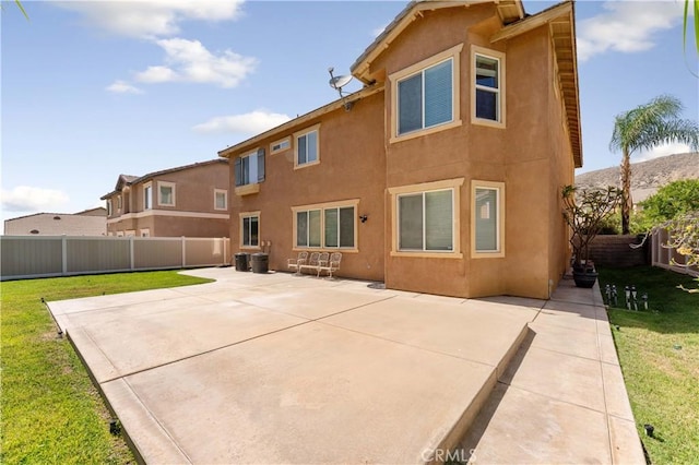 rear view of house featuring a yard, a fenced backyard, a patio, and stucco siding