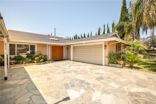 ranch-style house featuring concrete driveway, a shingled roof, and an attached garage