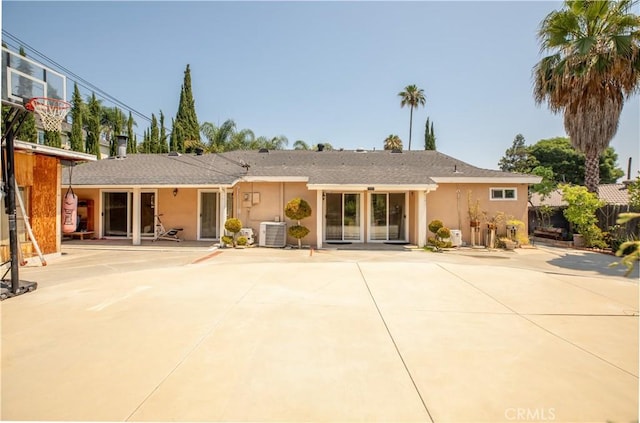 rear view of house with central air condition unit, a patio, and stucco siding