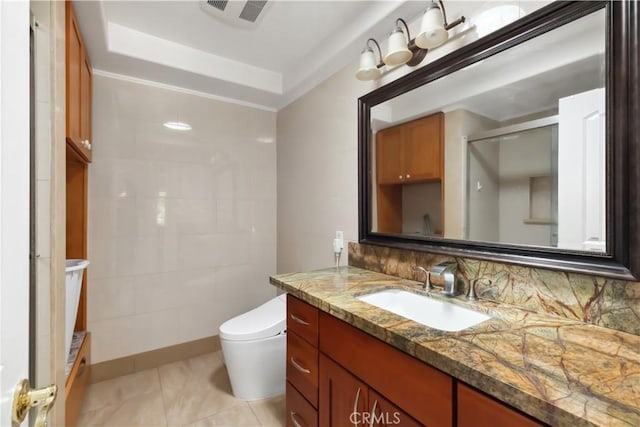 bathroom featuring visible vents, a raised ceiling, decorative backsplash, toilet, and vanity