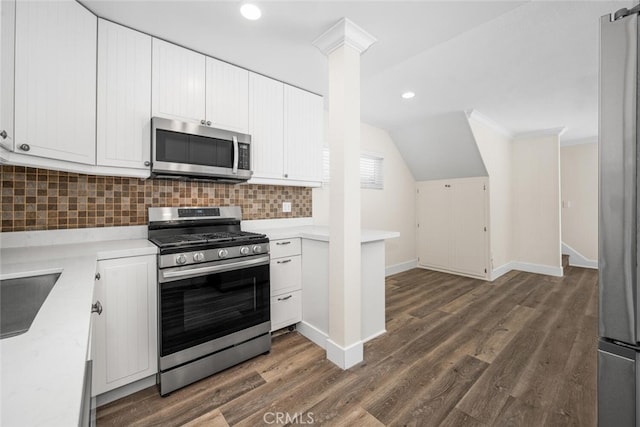 kitchen with dark wood-type flooring, baseboards, white cabinets, appliances with stainless steel finishes, and tasteful backsplash