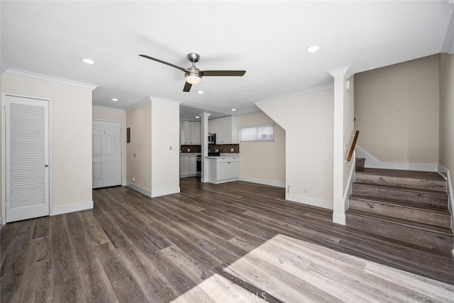 unfurnished living room with dark wood-type flooring, crown molding, baseboards, and stairs