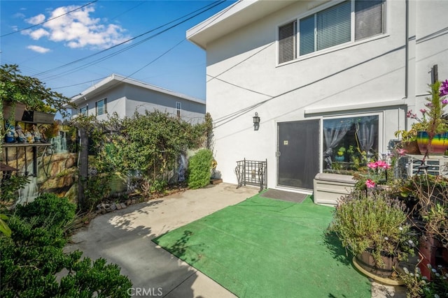 exterior space featuring fence, a yard, a patio, and stucco siding