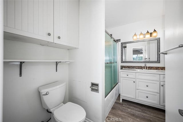 bathroom with shower / bath combination with glass door, vanity, toilet, and wood finished floors