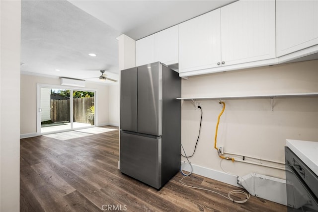 kitchen featuring baseboards, white cabinets, dark wood finished floors, a wall mounted air conditioner, and freestanding refrigerator