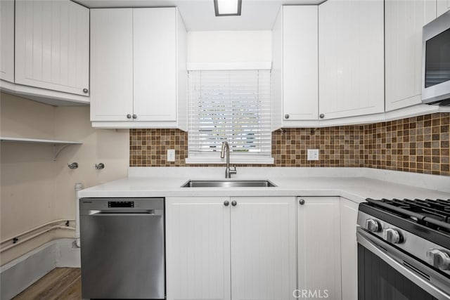 kitchen with light countertops, decorative backsplash, appliances with stainless steel finishes, white cabinetry, and a sink