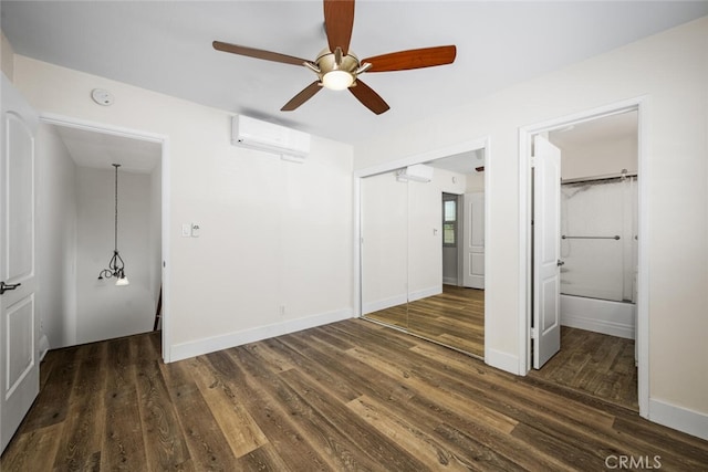 unfurnished bedroom with a closet, an AC wall unit, ceiling fan, wood finished floors, and baseboards