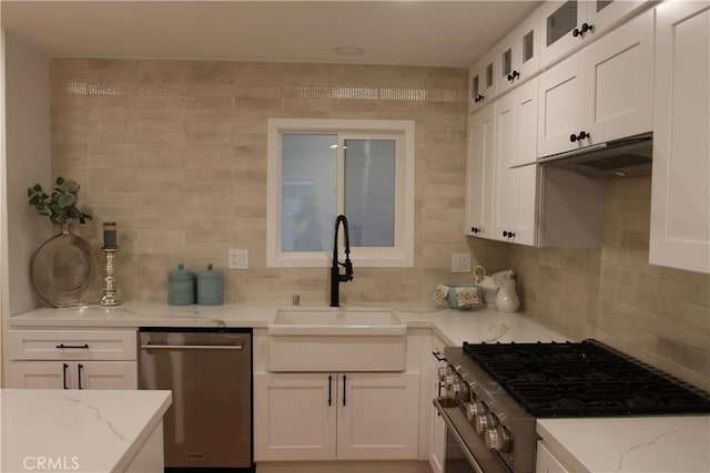 kitchen with stainless steel appliances, white cabinetry, a sink, and glass insert cabinets