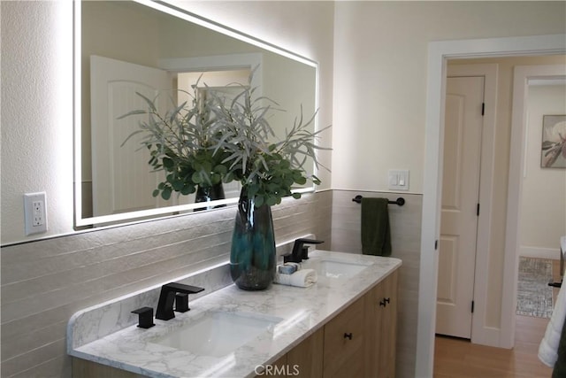 full bath with double vanity, a sink, and wood finished floors