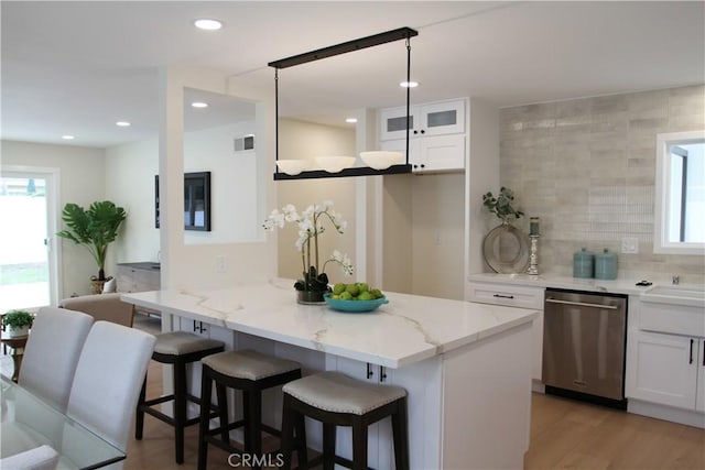 kitchen with a healthy amount of sunlight, stainless steel dishwasher, a breakfast bar area, and white cabinets