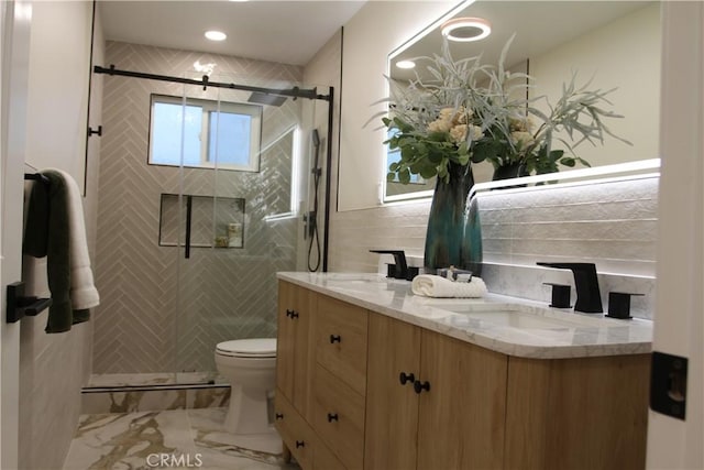 full bathroom with toilet, a sink, tile walls, a shower stall, and double vanity