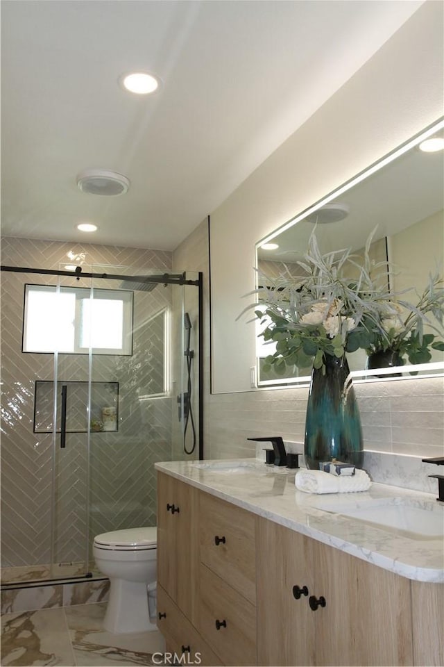 full bathroom featuring marble finish floor, tile walls, toilet, a shower stall, and vanity