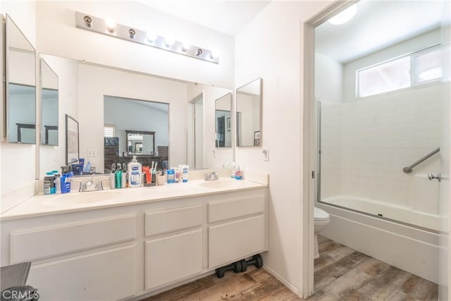 full bathroom featuring  shower combination, a sink, toilet, and wood finished floors