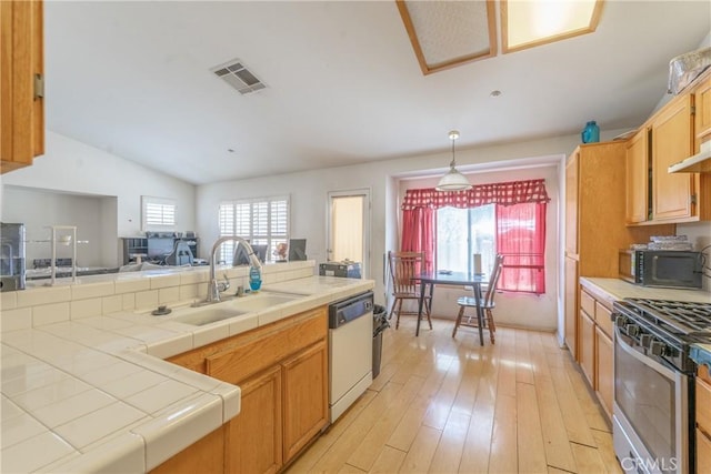 kitchen with visible vents, tile counters, dishwasher, black microwave, and a sink