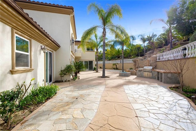 view of patio with exterior kitchen, fence, and grilling area