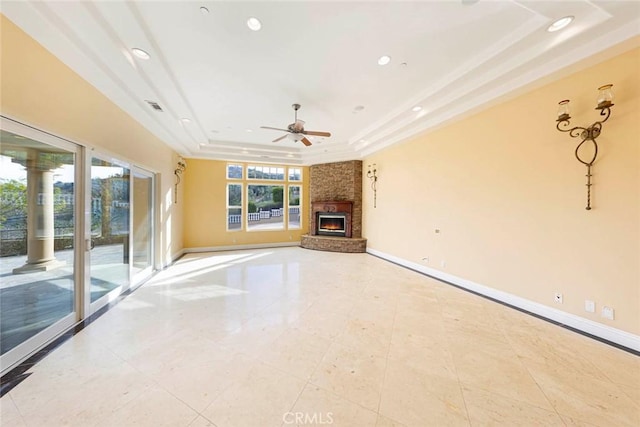 unfurnished living room featuring a tray ceiling, a fireplace, baseboards, and recessed lighting