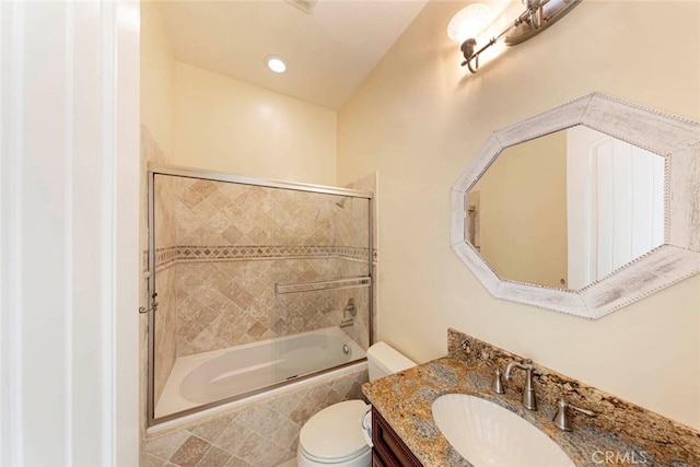 bathroom featuring toilet, shower / bath combination with glass door, and vanity