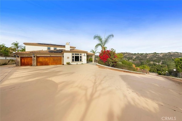 mediterranean / spanish home with an attached garage, driveway, solar panels, and stucco siding