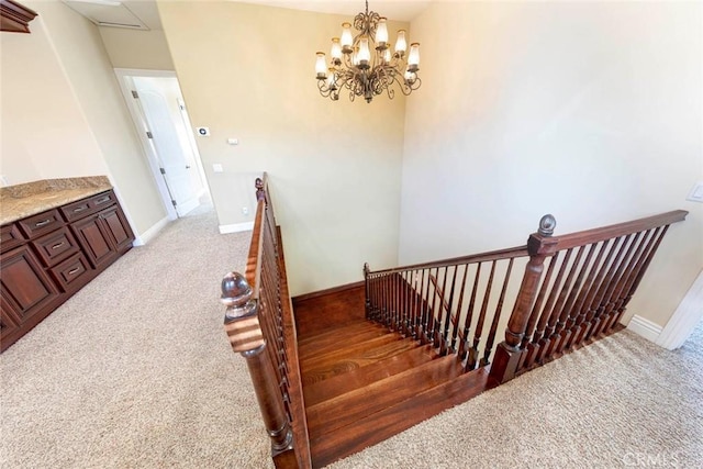 stairs with carpet, baseboards, and an inviting chandelier