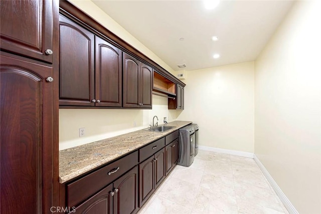 kitchen with recessed lighting, a sink, baseboards, dark brown cabinets, and light stone countertops